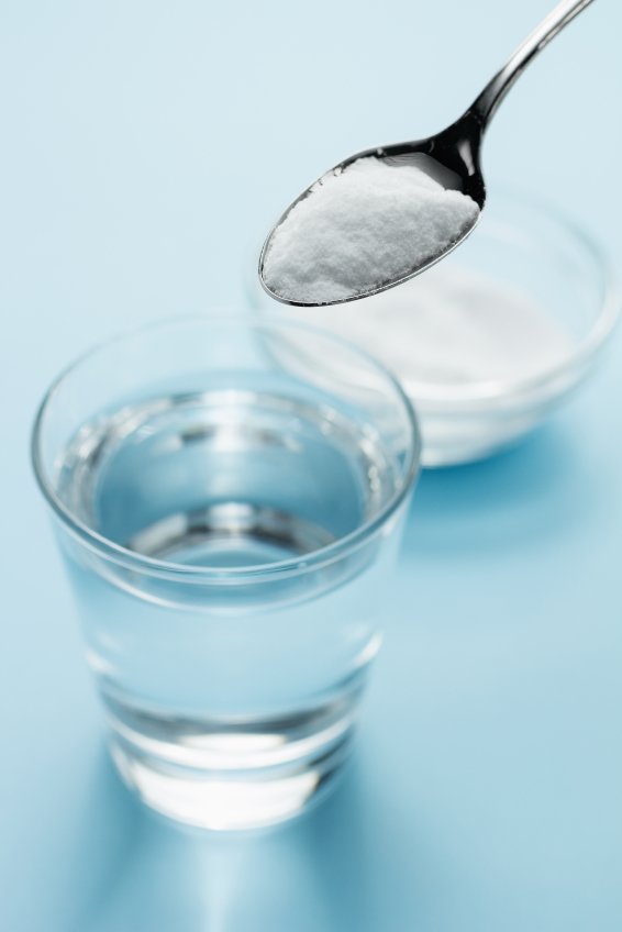 Bicarbonato de sodio y agua con una cuchara y un vaso. 