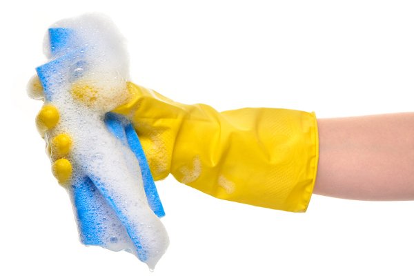Un guante amarillo que sostiene una esponja con burbujas. 