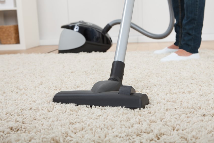 Se utiliza una aspiradora sobre una alfombra blanca.