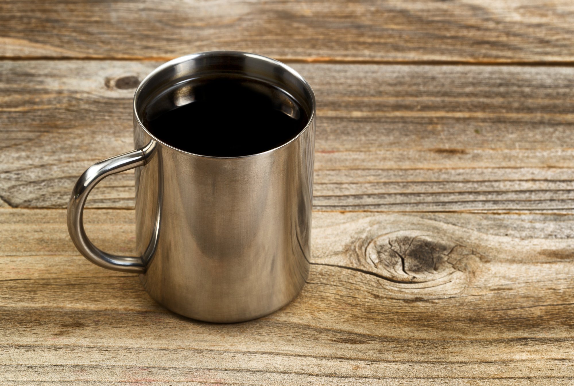 Una taza de café de acero inoxidable sobre madera.