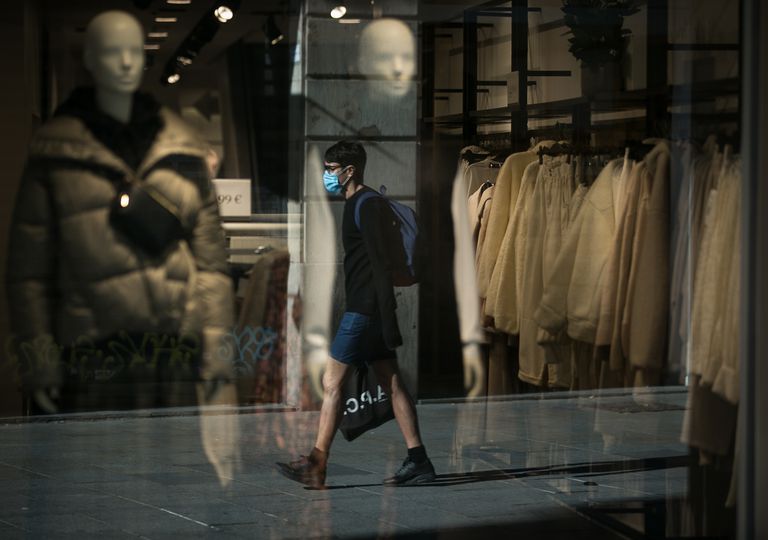 Un joven pasa ante el escaparate de una tienda en Barcelona.