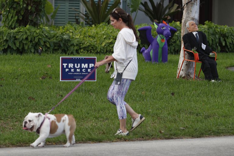 Una mujer pasea a su perro en una calle de Miami, este sábado 31 de octubre.