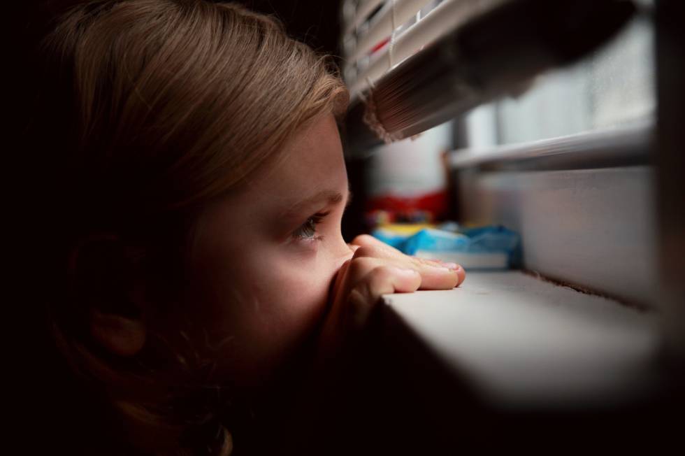 Una niña mira con miedo la calle.