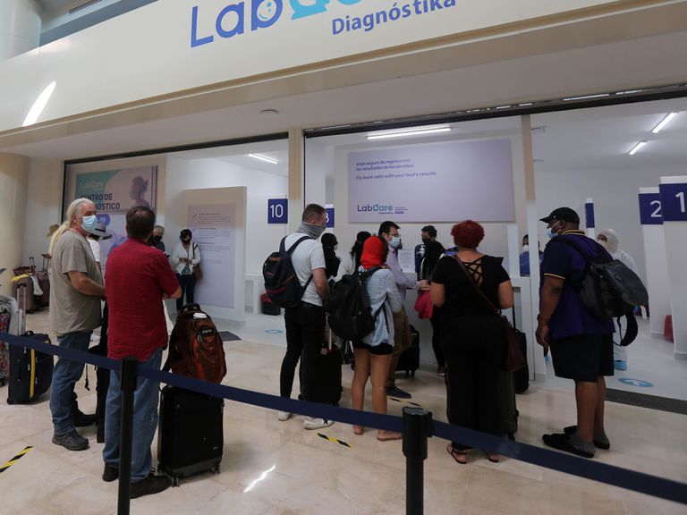 Turistas hacen fila para practicarse una prueba PCR en el Aeropuerto de Cancún.