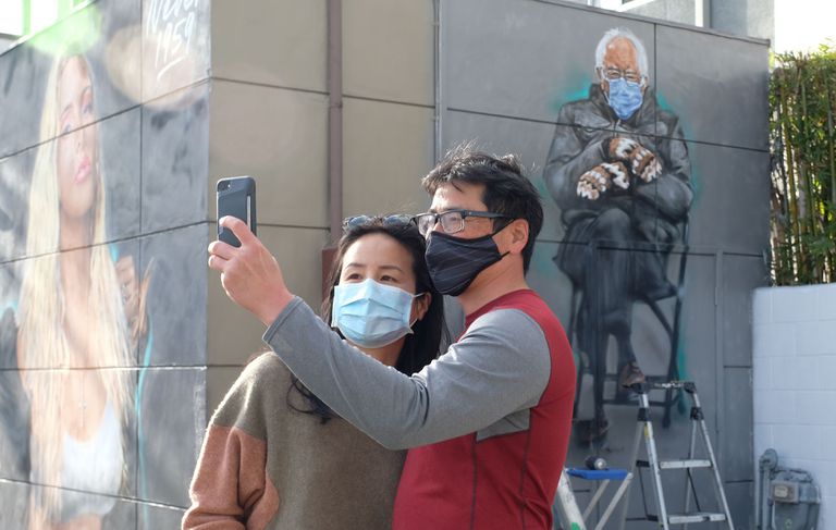 Dos personas se toman una foto junto a un mural del senador Bernie Sanders en Culver City, California.