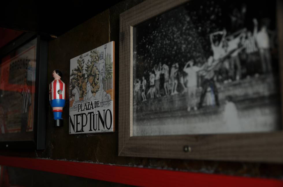 Un jugador colchonero de futbolín, el cartel de la plaza de Neptuno y una foto de atléticos festejando en la mítica fuente. Detalles en El rincón del Greco, un bar de cepa rojiblanca en Carabanchel (Madrid).