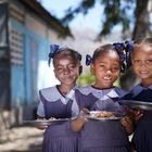 Tres niñas haitianas posan con sus platos de bulgur en su escuela. El Programa Mundial de Alimentos sirve hasta 250.000 menús a diario en las escuelas del país.