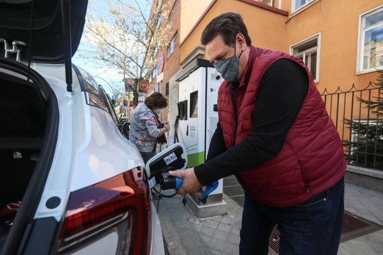 Un usuario de coche eléctrico recarga su vehículo en un punto situado en la calle en el centro de Madrid.