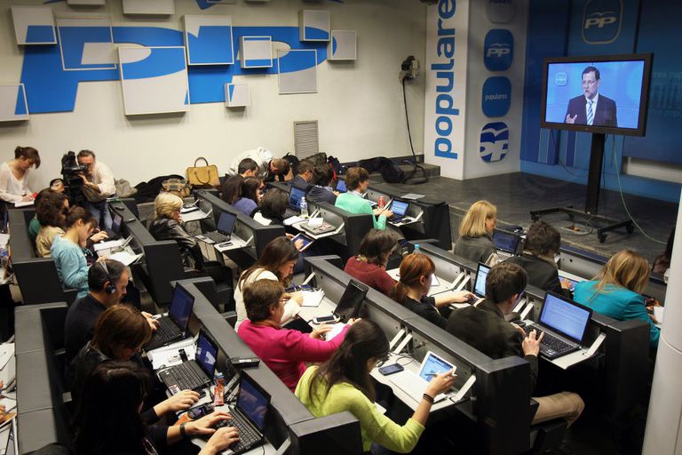 Periodistas atienden una intervención del presidente del Gobierno Mariano Rajoy a través de una pantalla de plasma en la sala de prensa del PP en 2013.