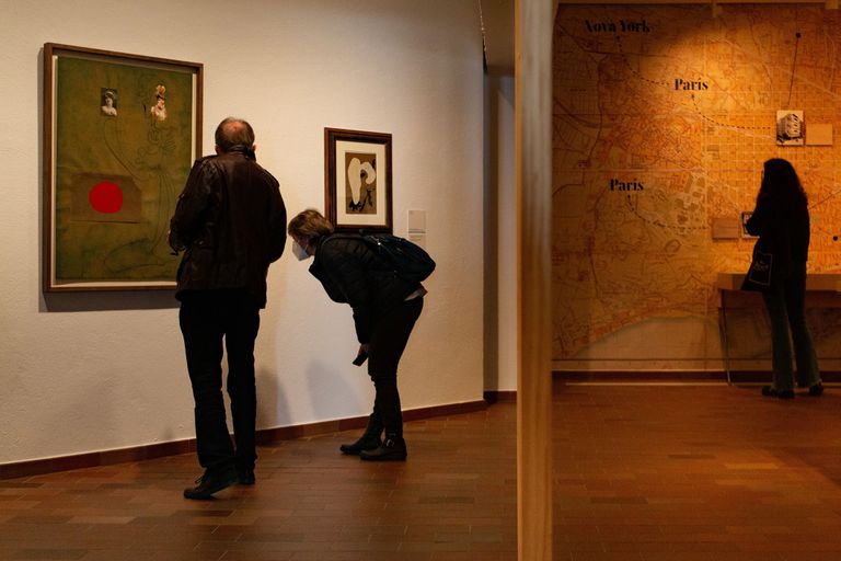 Dos personas miran la obra "Sin Título" un gran dibujo realizado por Joan Miró en 1933, al lado de un 'collage' de 1934 y, al fondo, el mapa con las cinco exposiciones que el pintor celebró con ADLAN en Barcelona, en la exposición que se puede ver en la Fundación Miró hasta julio.