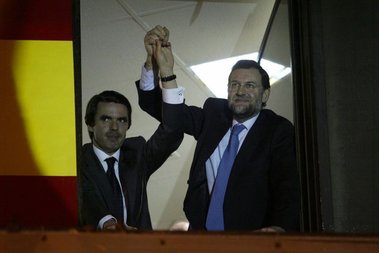 José María Aznar y Mariano Rajoy saludan a los simpatizantes del PP desde la ventana de la sede del partido de Madrid, tras los resultados de las elecciones generales del 14-M del 2000.