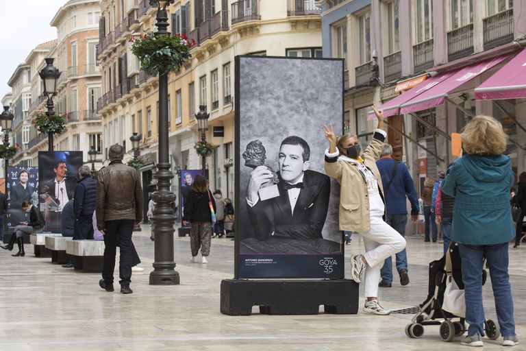 Una mujer se fotografía junto a una imagen de Antonio Banderas en calle Larios, en Málaga.