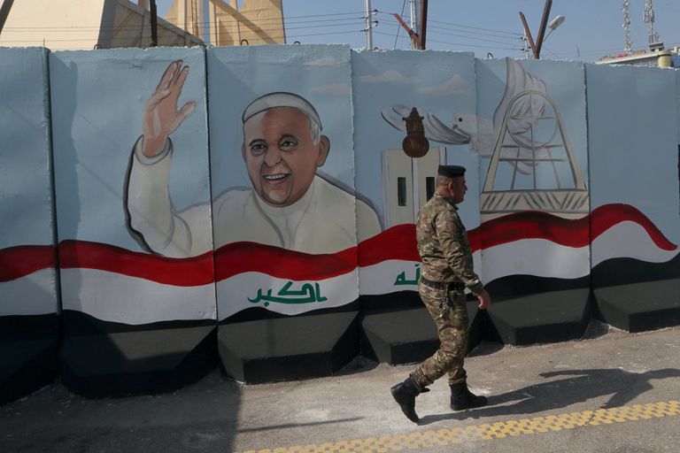 Un soldado iraquí pasa delante de un muro de hormigón decorado con la efigie del Papa Francisco, ante su próxima visita a Irak.