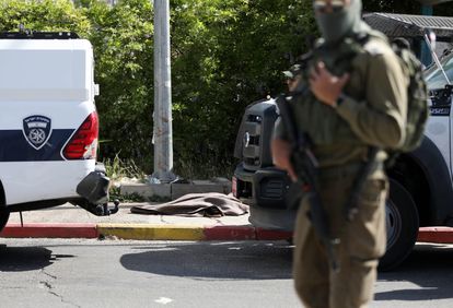 Un soldado israelí monta guardia ante el cadáver de una palestina de 60 años abatida por las tropas a las que amenazó con cuchillo, el domingo en el cruce de Gush Etzion, al sur de Belén (Cisjordania).
