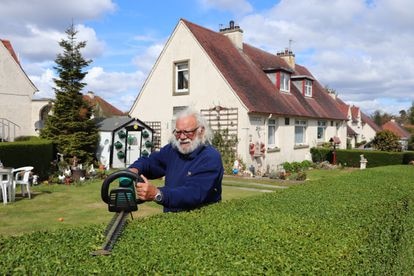 John Boath poda el seto de su jardín este miércoles en West Pilton, Edimburgo. / RAFA DE MIGUEL