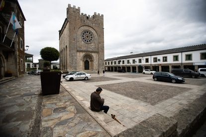 Un hombre sentado en la plaza de la iglesia de San Nicolás en Portomarín (Lugo).