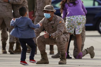Uno de los militares españoles llegados de Afganistán abraza a un niño que ha acudido a recibirlo en la base de Torrejón de Ardoz, 