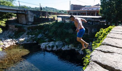 Un adolescente salta desde el puente de Cuartos a una de las pozas naturales que se forman, en Losar de la Vera.