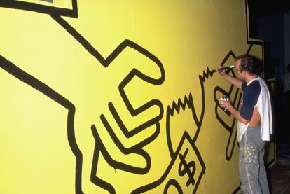 El artista Keith Haring pinta su trabajo en una gran pared amarilla para una exposición de arte en mayo de 1985.