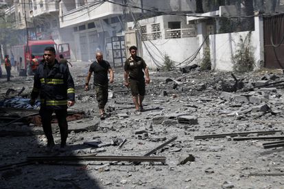 Unos bomberos inspeccionan una zona derruida por un bombardeo, este domingo en ciudad de Gaza.