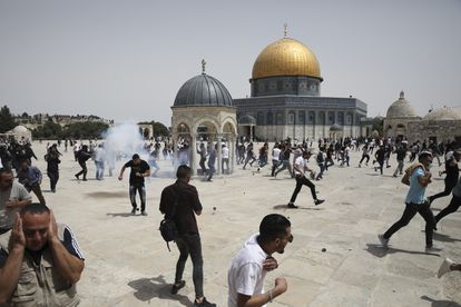Decenas de palestinos corren tras el lanzamiento de granadas aturdidoras por agentes israelíes, este viernes en la Explanada de las Mezquitas de Jerusalén.