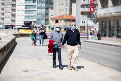 Varias personas pasean por el Paseo Marítimo de Sanxenxo, en Pontevedra, Galicia (España).