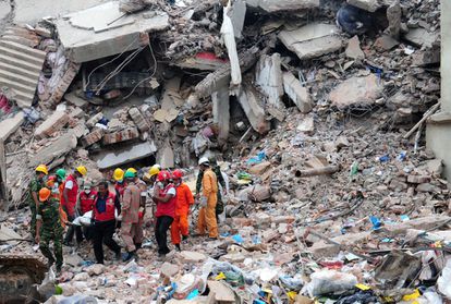 Varios miembros del personal de emergencias rescata el cadáver de una persona entre los escombros del edificio Rana Plaza de Dacca, en Bangladés, donde se ubicaban varias fábricas textiles, en abril de 2013. El derrumbe provocó más de mil muertos.