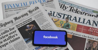 El logo de Facebook en un móvil junto a periódicos australianos. 