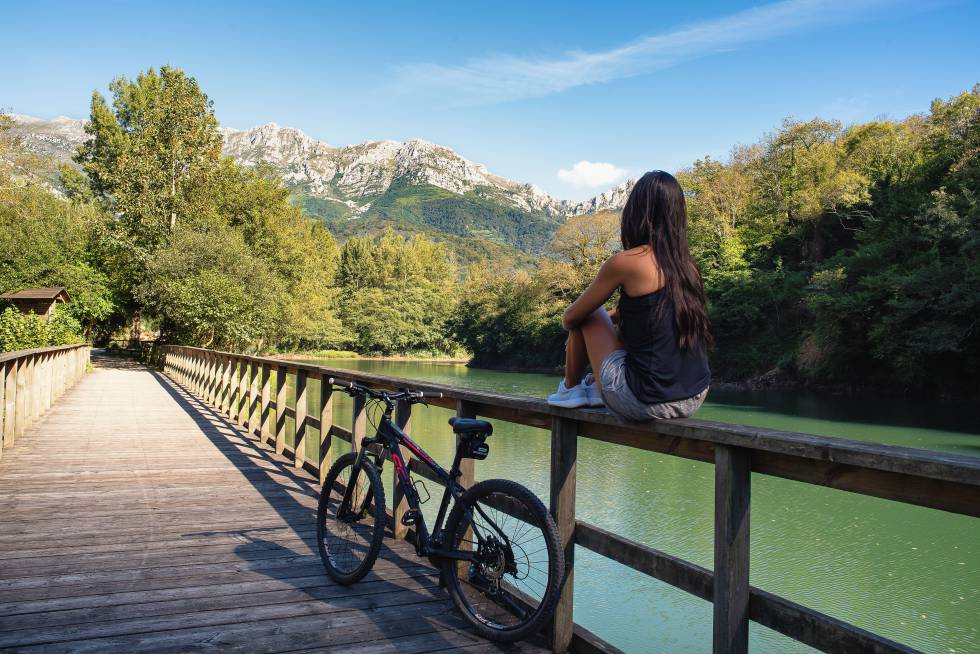 Una ciclista hace un alto en la Senda del Oso, en el puente que atraviesa el embalse de Valdemurio, en Asturias.