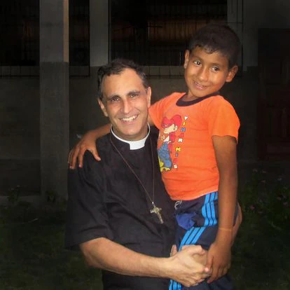El padre Doñoro sujeta en brazos uno de los niños acogidos en Hogar Nazaret.