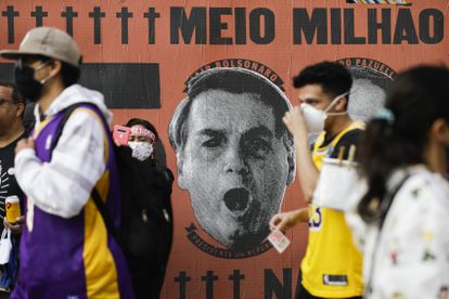 Manifestantes izquierdistas pasan, el sábado pasado en São Paulo, ante un mural que culpa al presidente Bolsonaro del medio millón de muertos por el covid-19.