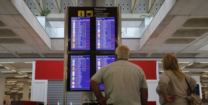 Pasajeros consultando vuelos en el aeropuerto de Palma de Mallorca.