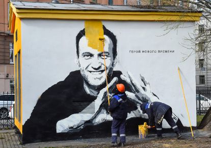 Un trabajador pinta sobre un grafiti con el retrato del opositor ruso Alexéi Navalni.