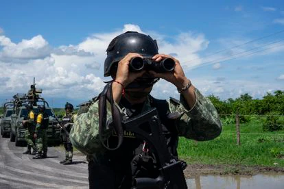 Un militar mira por sus prismáticos en dirección a la zona donde se encuentra el retén del Cartel Jalisco Nueva Generación (CJNG).