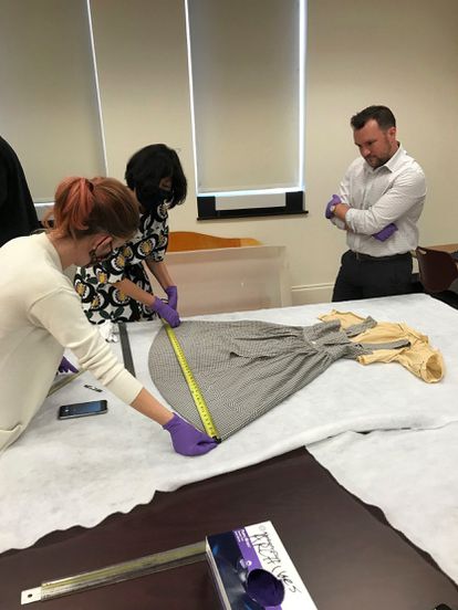Los expertos del Museo de Historia Estadounidense del Instituto Smithsonian (de izquierda a derecha) Dawn Wallace, Sunae Park Evans y Ryan Lintelman examinan el vestido de Dorothy de 'El mago de Oz' encontrado en la Universidad Católica de América, en Washington.
