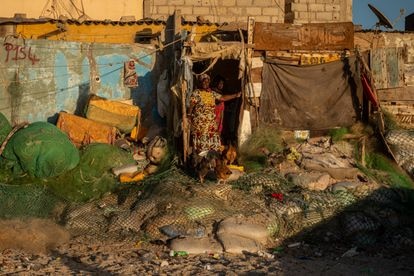 Una mujer alimenta a sus gallinas frente a la casa que se ha construido sobre los restos de viviendas que el mar ha destruido.
