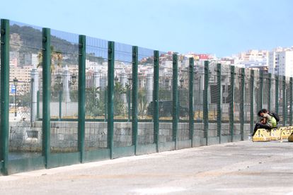 Dos menores descansan en una zona de restaurantes en el muelle de Ceuta.