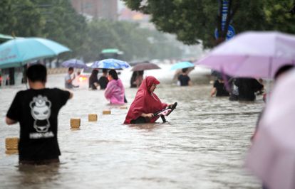 Gente caminando por una carretera inundada de Zhengzhou, en la provincia central china de Henan, el martes 20 de julio de 2021.