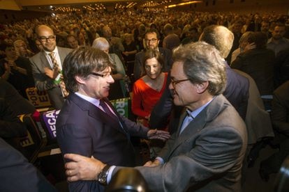Carles Puigdemont y Artur Mas se saludan, en presencia de Carme Forcadell, durante el acto central del Pacto Nacional por el Referéndum.