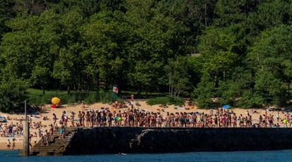 Grupos de jóvenes hacen cola para saltar al mar en el espigón de la playa de la Magdalena de Santander este lunes.