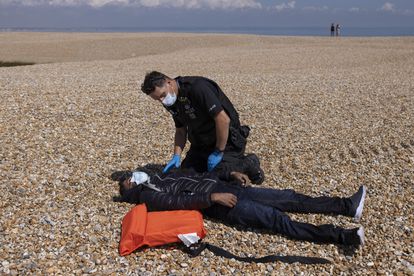 Un policía revisa el estado de un hombre colapsado en la playa de Dungeness el 4 de agosto de 2021.