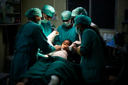 En la sala de operaciones, un cirujano y los médicos del hospital operan a Jaya para liberar su brazo.