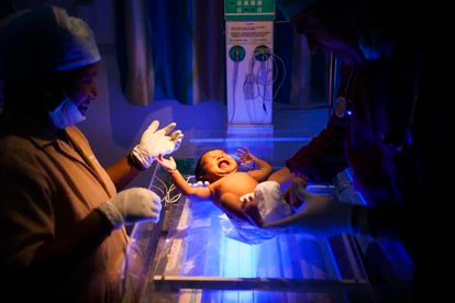 El doctor Rakh y una enfermera examinan a una niña recién nacida que llora en la incubadora.