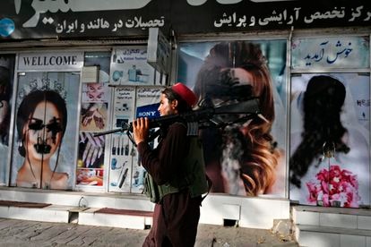 Un talibán pasa por delante de un salón de belleza con las imágenes de mujeres pintadas con aerosol, en Kabul este 18 de agosto.