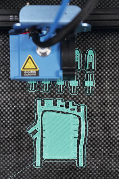 Una impresora 3D fabrica la primera capa de una palma y unos dedos para un pedido de mano derecha para un niño.