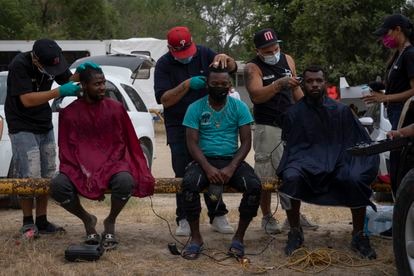 Migrantes haitianos reciben un corte de pelo gratuito en el parque donde se están albergando en Ciudad Acuña (México), este martes.