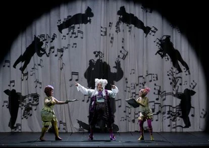 Don Magnifico, en su aria del Acto II, junto a sus dos hijas y con figuras proyectadas de Rossini tocando diversos instrumentos.