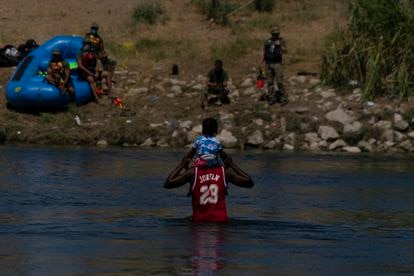 Un hombre haitiano y su hijo cruzan el Río Bravo hacia Del Río (Texas), este jueves.