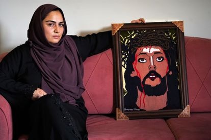 Maryam Sadat junto a un cuadro con el rostro de Cristo hecho en punto de cruz