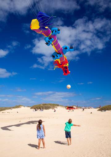 Dos niños vuelan un dragón en el Festival Internacional de Cometas, en el parque natural de las Dunas de Corralejo, en Fuerteventura.